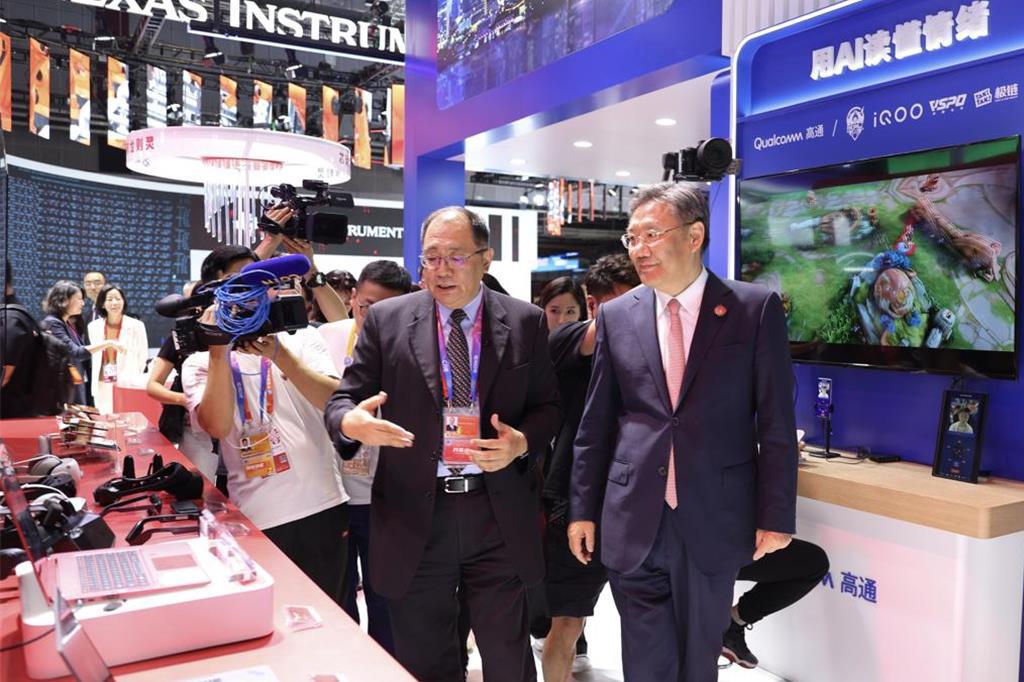 中國大陸商務部部長王文濤（前）在進博會期間，參觀高通公司展台，並與企業交流。（中新社）